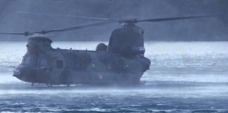 Chinook landing on a lake to retrieve special forces in a zodiac