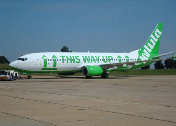 A Kulula Airlines Boeing 737 aircraft with a humorous green and white "THIS WAY UP" paint scheme (livery) and arrows pointing upwards along its fuselage.