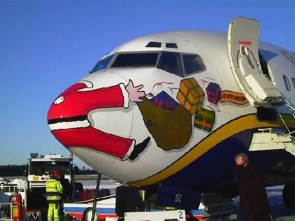 A Ryanair Boeing 737 aircraft with a humorous Christmas-themed paint job (livery) depicting Santa Claus appearing to be stuck in the plane's nose, holding a sack of presents.